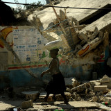 Haitian people walk by the damaged buildings in downtown Port au Prince, Haiti on January 18, 201...